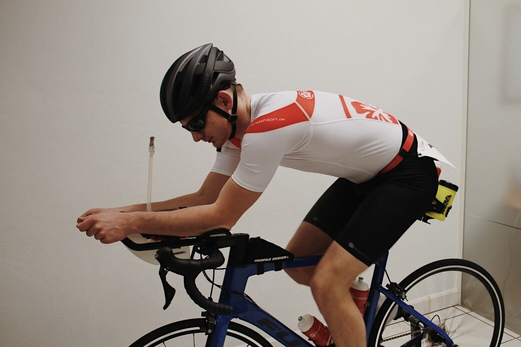 Ein männlicher Triathlet sitzt auf einem Rennrad mit Triathlon-Lenkeraufsatz