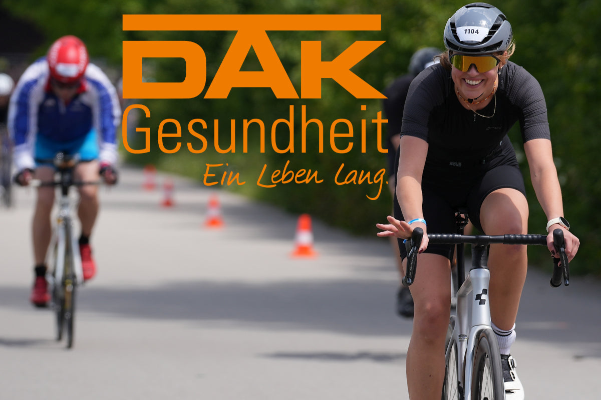 Titelbild: eine Radfahrerin auf dem Rennrad von vorn lächelt in die Kamera. Daneben das DAK Logo
