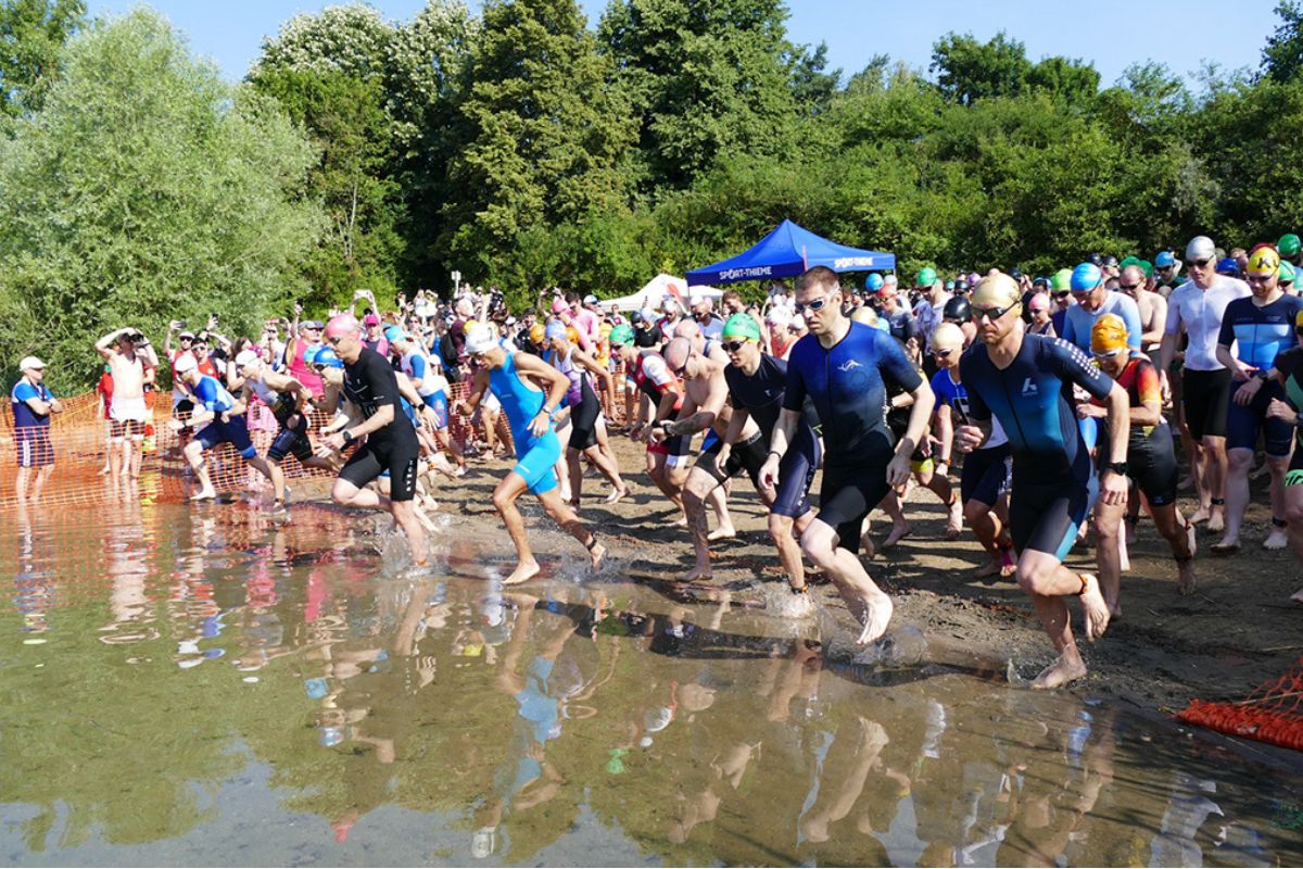 Triathleten bei ihrem Start ins Wasser fotografiert.